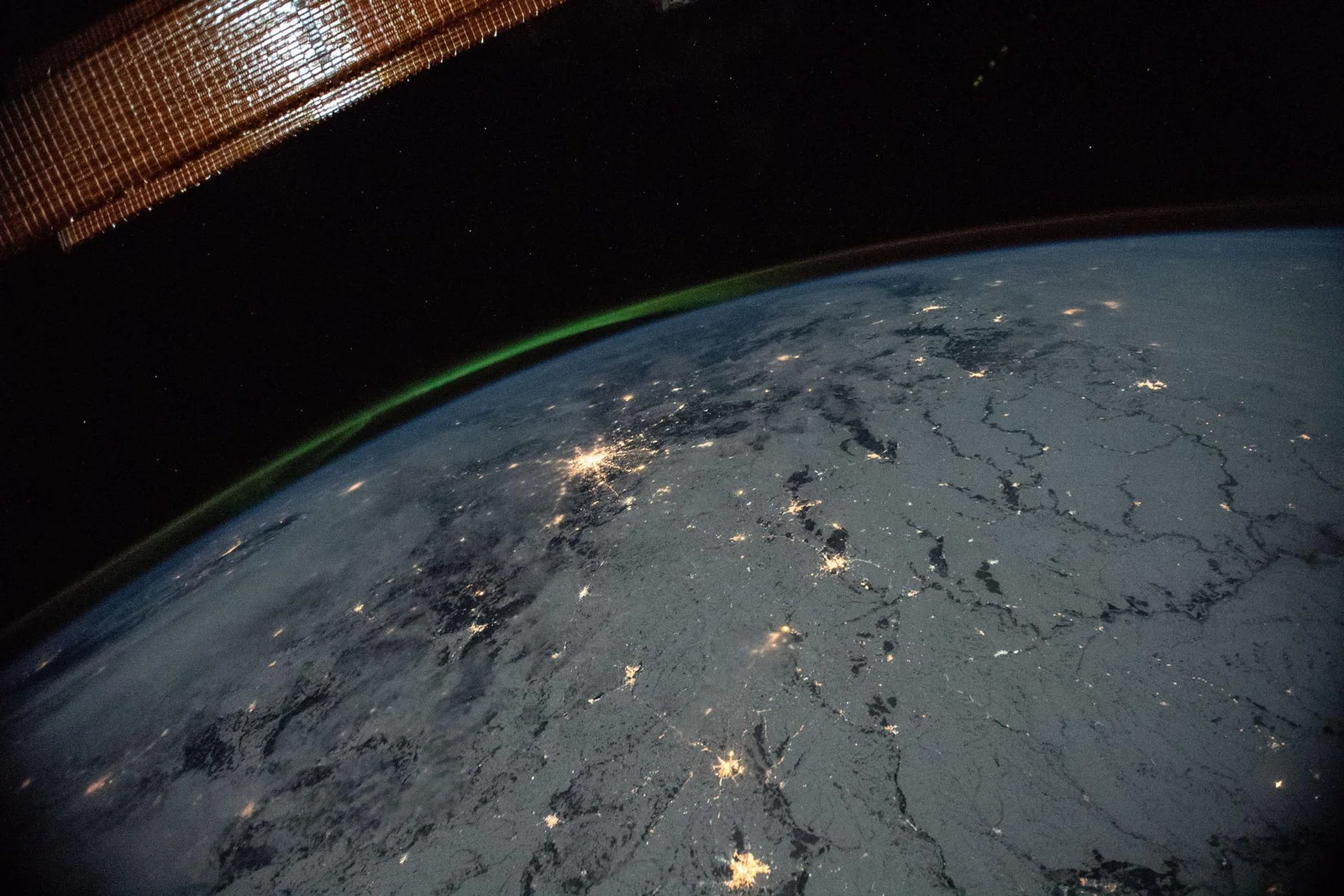 Night lights and an aurora over Earth, seen from the International Space Station